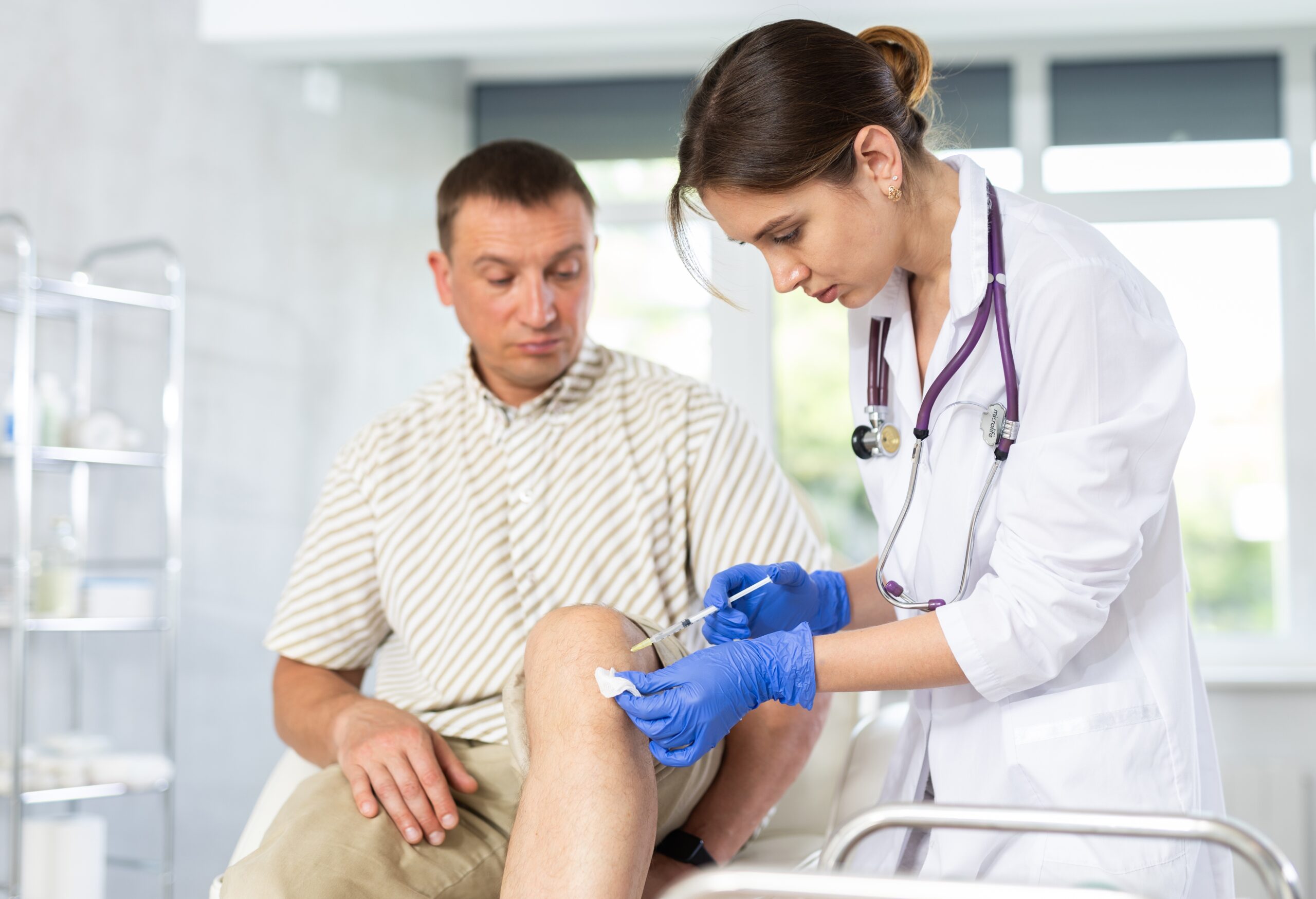 Young,Female,Doctor,Performs,Intra-articular,Injection,Treatment,Of,Knee,Bursitis