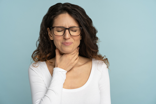 Woman holding her throat in pain, showing common symptoms of strep throat