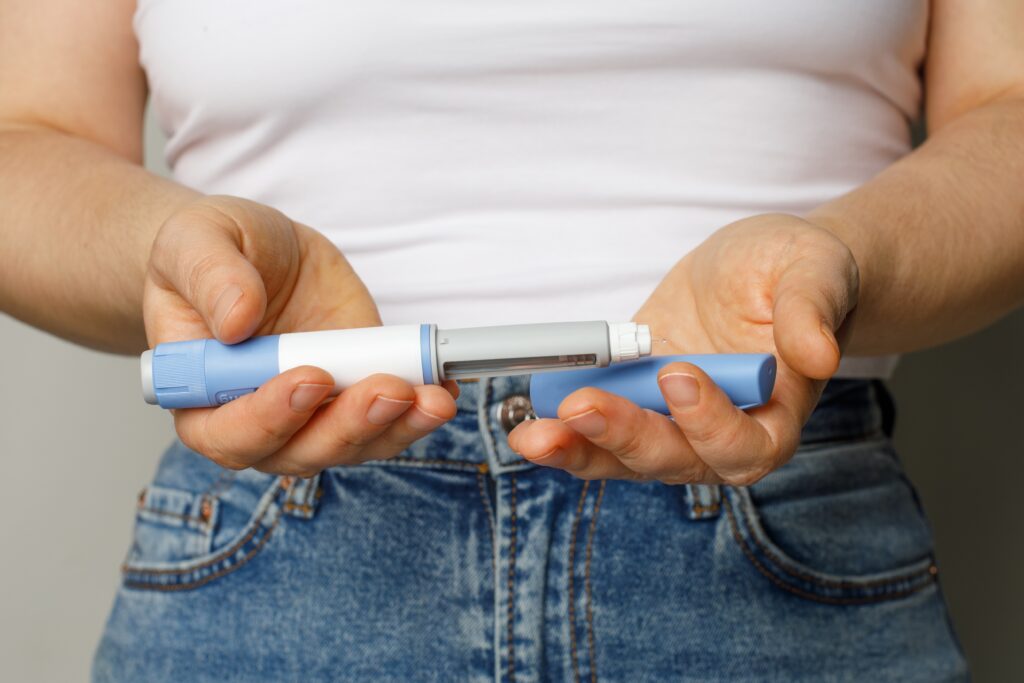 Person holding a semaglutide injection pen while preparing the medication for weight loss treatment