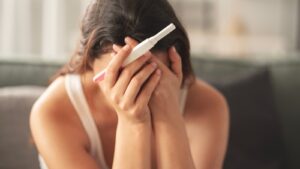 Woman looking concerned while tracking menstrual cycle on calendar, representing early signs of infertility in women