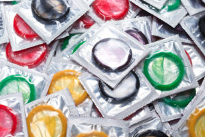 Condoms being placed on fingers to demonstrate correct use for safe sex and protection against pregnancy and stis