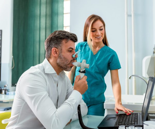 Professional,Female,Nurse,In,Teal,Scrubs,Assisting,A,Male,Patient